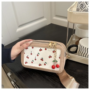 Detail view of cream square crossbody bag with cherry prints and wide woven strap