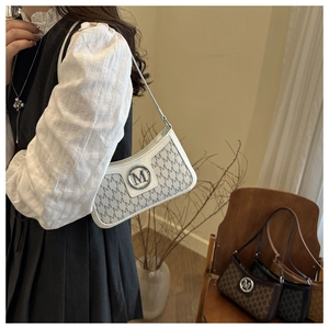 Close-up of vintage underarm bag with letter pattern and metal M logo on ivory leather