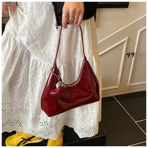 Detail of red patent leather half-moon baguette bag with silver zipper and heart charm