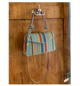 Close-up of bohemian multi-color striped woven crossbody bag with flip cover design