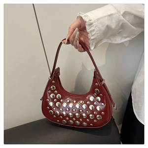 Detailed close-up of red hobo bag with silver metallic rivets and glossy leather finish