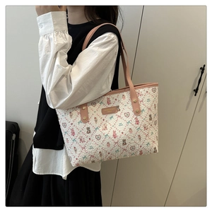 Detail of white tweed tote bag with pink cartoon bear prints and gold logo plaque