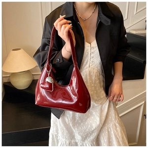 Detail of dark red patent leather baguette bag with silver heart charm and brand embossing