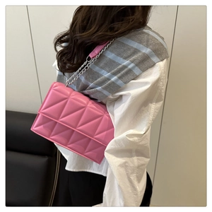 Détail d'un sac bandoulière matelassé rose vif avec chaîne argentée sur mannequin