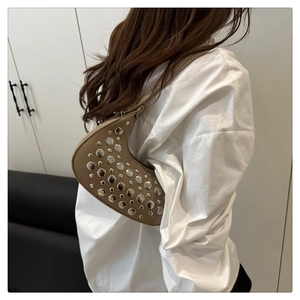 Detail of khaki crescent shoulder bag with silver stud accents on a female model