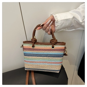Détail de la texture en paille tressée colorée et de l'anse en cuir marron du sac seau d'été