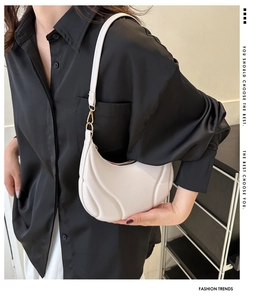 Detail of white pleated crescent shoulder bag with golden metallic hardware and strap