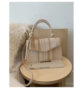 Detail of beige and brown striped straw woven bag with round handle and metal rings