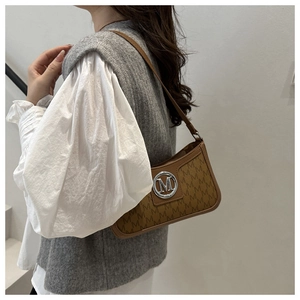 Detail of vintage brown underarm bag with letter print and silver metallic logo