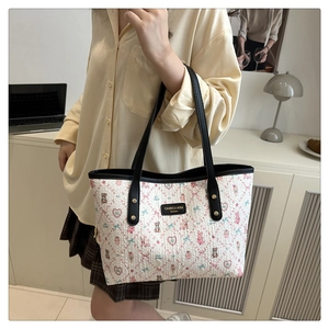 Close-up of cream tote bag with bear and floral prints featuring black shoulder straps