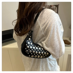 Detail of black crescent shoulder bag featuring silver metal rivets and matte leather