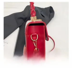 Detail of red leather handbag showing gold D-ring hardware and twisted rope handle