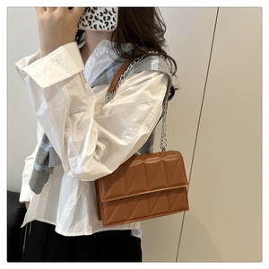 Détail d'un sac bandoulière marron matelassé avec chaîne argentée et cuir PU brillant