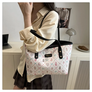 Detail of white tote bag featuring colorful cartoon prints and leather brand tag