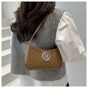 Detail of vintage underarm bag with M-letter monogram pattern and silver metal logo