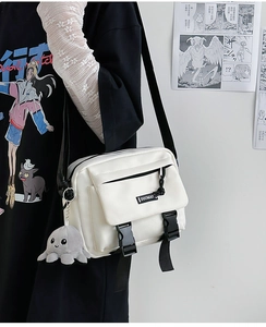 Detailed view of white nylon messenger bag with flap buckles and plush octopus charm