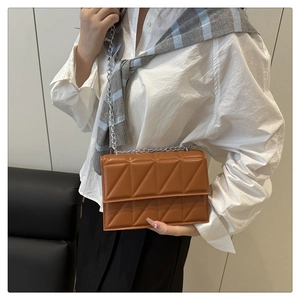 Détail du sac à bandoulière marron avec texture matelassée triangle et chaîne argentée