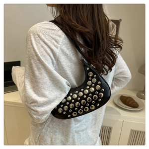 Detail of black crescent shoulder bag with silver rivet studs and smooth leather texture