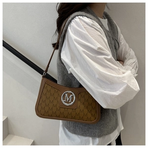 Close-up of vintage brown underarm bag with letter M print and silver metal logo buckle