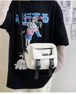 Close-up of a white canvas messenger bag featuring dual buckles and a cute octopus charm