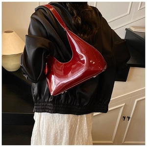 Detail of dark red patent leather shoulder bag with a modern streamlined silhouette