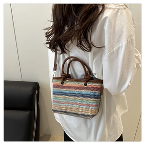 Détail du sac seau en paille colorée avec poignées en cuir marron et anneaux dorés