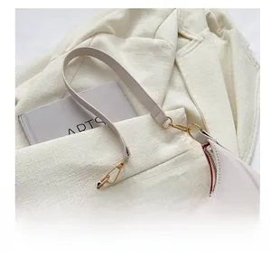 Close-up of cream crescent underarm bag with gold hooks on a textured blazer