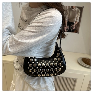 Detailed close-up of a black crescent bag with silver metallic rivets and leather strap