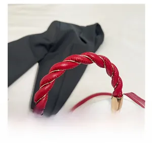 Detail of red braided handle and golden hardware on white cherry print handbag