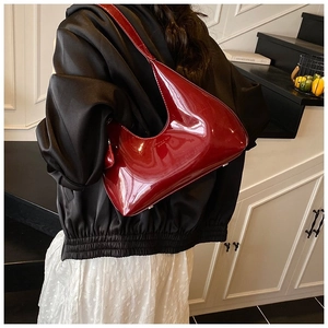 Detail view of the glossy dark red patent leather baguette bag with silver hardware accents