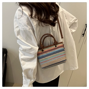 Détail du sac seau en paille tissée colorée avec poignées en cuir brun et rayures