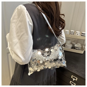 Detail of silver sequin shoulder bag on model showing metallic sparkle and slim strap