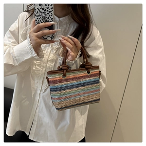 Détail du sac seau en paille tressée arc-en-ciel avec anses en cuir marron et anneaux
