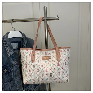 Detail of white embossed tote bag featuring cute cartoon rabbit prints and pink leather straps