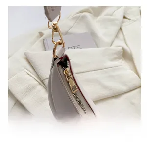 Detailed macro shot of the smooth gold-tone metal zipper on a cream leather shoulder bag