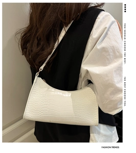 Close-up of white crocodile pattern texture on a minimalist leather underarm bag