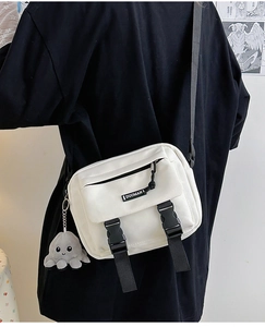 Detail of white canvas crossbody bag featuring tactical buckles and octopus plush charm