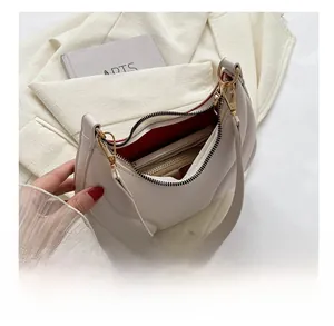 Detailed view of white pleated underarm bag with red lining and interior capacity