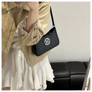 Close-up of vintage black underarm bag with M-letter jacquard pattern and metal logo
