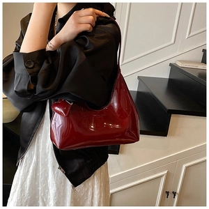 Detail of burgundy patent leather hobo bag with heart charm shown in a lifestyle scene