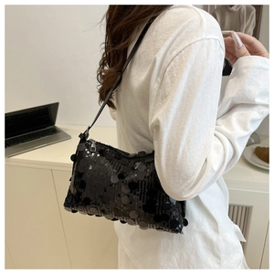 Detail of black sequined underarm bag with large round sequins and leather shoulder strap