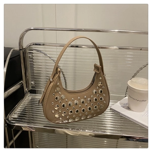 Detailed macro view of khaki crescent hobo bag with silver rivets on metal shelf
