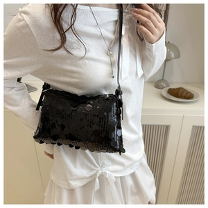 Close-up of black sequined crossbody bag with metallic shimmer and leather strap