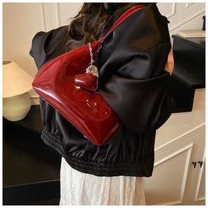 Detailed view of heart-shaped patent leather shoulder bag with matching heart charm charm