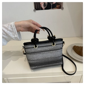 Détail d'un sac seau tissé avec poignée en cuir nouée et ferrures dorées