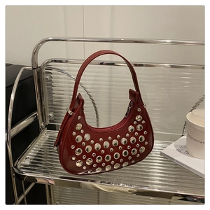 Detailed view of dark red crescent bag with silver rivet studs and a top handle