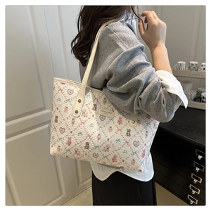 Detailed close-up of cream tote bag with pink cartoon bear prints and metal rivets