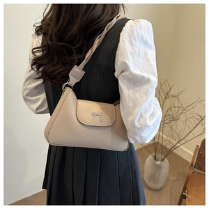 Detalle de bolso en cuero beige con hebilla de lazo plateado y correa con diseño trenzado