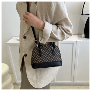 Chic brown shell bag with gold geometric patterns worn with a beige blazer suit