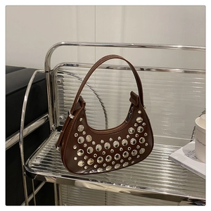 Detail of a brown crescent shoulder bag featuring stylish silver rivets and glossy finish